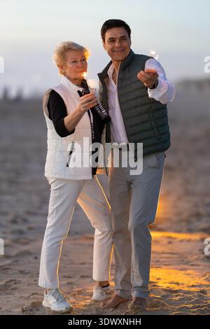 Ein Paar feiert den Erfolg am Strand bei Sonnenuntergang Stockfoto