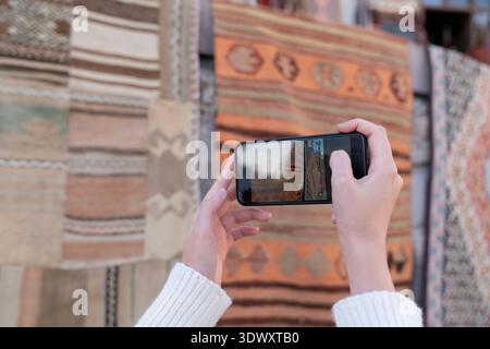Touristen fotografieren Teppiche mit ihrem Handy auf der Straße Stockfoto