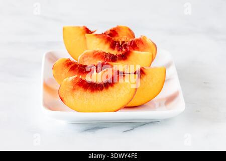 Freie Steinpfirsichsegmente auf einer weißen Schale, bereit zum Essen. Stockfoto