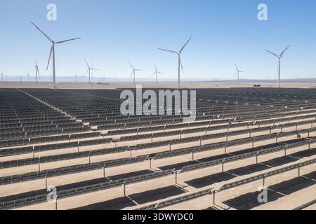 Luftaufnahme eines großen Hybrid-Kraftwerks für erneuerbare Energien, das Solarpaneele und Windturbinen in einer Wüstenumgebung kombiniert, mit nachhaltigem po Stockfoto