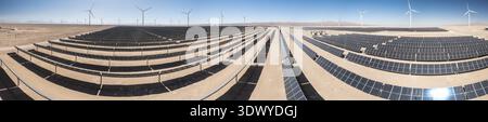 Luftaufnahme von großen Solarpaneelen und Windturbinen in einer Wüstenumgebung unter klarem blauem Himmel Stockfoto