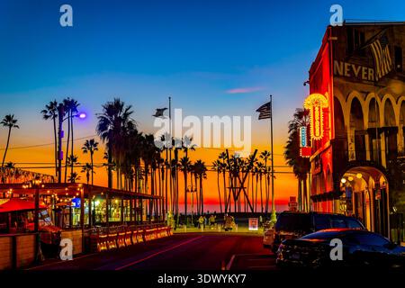 Los Angeles, CA, USA - 01. Dezember 2025: Intensive Sonnenuntergangsfarben leuchten hinter Silhouettenpalmen entlang Santa Monica und Venice Beach in Kalifornien Stockfoto