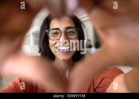 Brasilianische Frau, die mit ihren Händen Herzform macht, Nahaufnahme Stockfoto