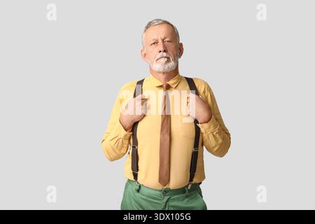 Schöner reifer Mann mit stilvoller Krawatte auf grauem Hintergrund Stockfoto