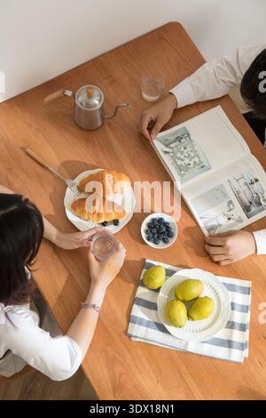 Paare genießen morgens Frühstück mit Croissants Birnen und Kaffee zu Hause Stockfoto