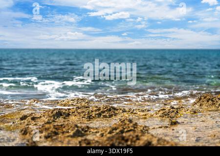 Blick auf das Meer an einem sonnigen Tag mit Wellen, die an der felsigen Küste krachen, perfektes Urlaubsfoto Stockfoto