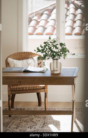 Helles, minimalistisches Home Office-Interieur mit Holzschreibtisch, Stuhl und natürlichem Fensterlicht in einem modernen Wohnhaus. Stockfoto