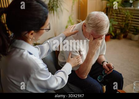 Eine Kaukasische Frau Mittleren Alters Tröstet Einen Älteren Kaukasischen Mann, Der In Not Leidet Stockfoto