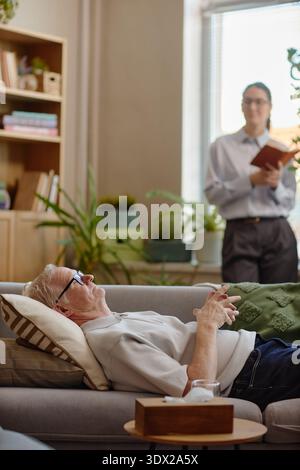 Senior-kaukasischer Mann, der auf der Couch liegt und sich einer psychologischen Beratung unterzieht Stockfoto
