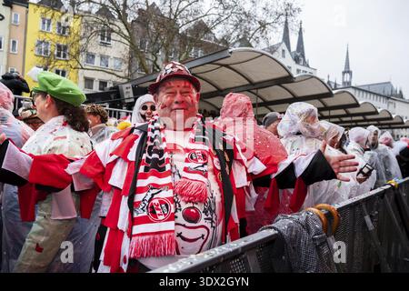 Mann in fröhlichem Karnevalsoutfit in einer regnerischen Festivalumgebung mit vielen Menschen in der Nähe, bei einer lebhaften Outdoor-Veranstaltung zur Weiberfastnacht, Alter Ma Stockfoto
