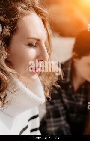 Frau Profil Portrait ruhige lockige Frau in gestreiftem Rollkragenpullover, die sich im warmen Sonnenuntergangslicht draußen sonnt Stockfoto
