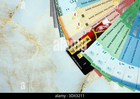 KIEW, UKRAINE - 28. JANUAR 2026 Maybank-Karte und malaysische Ringgit-Geldscheine auf dem Tisch in Nahaufnahme. Maybank ist die beliebteste Bank in Malaysia Stockfoto