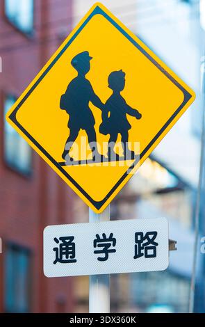 TOKIO – 05. Januar: Traditionelles gelbes Straßenschulschild an der Schulstraße in Tokio am 05. Januar. 2024 in Japan. Vertikales Bild Stockfoto