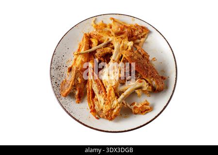 Knochen und Abfall von mariniertem gegrilltem Huhn auf rustikalem Teller nach dem Abendessen Nahaufnahme isoliert auf weißem Hintergrund. Stockfoto