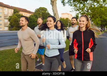 Gruppe von Läufern, die im Sommer im Stadtpark joggen, Team läuft entlang der Straße Stockfoto