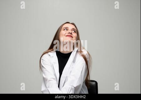Junge Frau, die tagträumt mit einem lächelnden Ausdruck, in Gedanken aufblickt, sich neue Ideen vorstellt Stockfoto