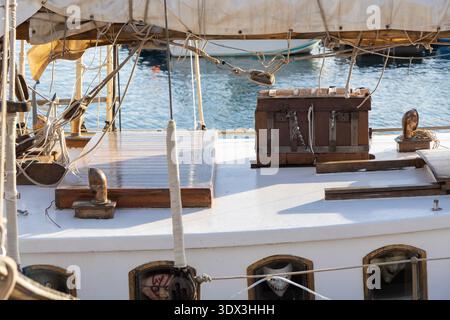 Eine Holzkiste liegt auf dem Deck eines Schiffes in Cartagena, Spanien, mit dem Meer und historischen maritimen Elementen im Hintergrund Stockfoto