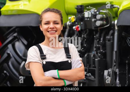 Porträt einer selbstbewussten Mechanikerin, die in der Nähe des Traktors steht Stockfoto