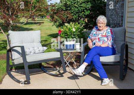 Eine ältere Frau sitzt entspannt auf ihrer hinteren Terrasse in Warren, Indiana, USA. Stockfoto