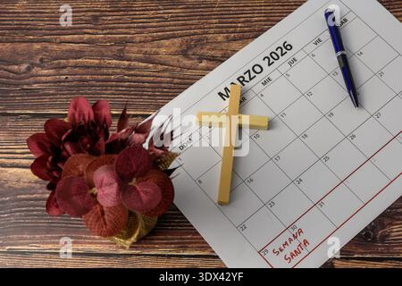 Blick von oben auf den Kalender März 2026 mit Holzkreuz, Stift und Blumen, Konzept des Karwochenplans, christlicher glaube und Ostererinnerung. Stockfoto