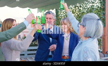 Freunde, die mit Flaschen tosten, genießen eine Dachparty Stockfoto