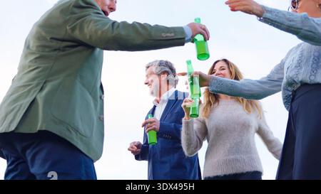 Freunde, die im Freien mit Bierflaschen tosten, feiern den Erfolg Stockfoto