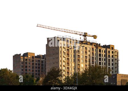 Im Bau hohes mehrstöckiges Gebäude mit Turmbaukran isoliert auf weißem Hintergrund. Leer für Industrie, Immobilieninvestitionen Stockfoto