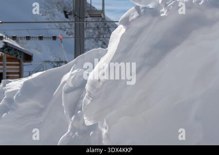Schneeschwehenstruktur mit Schichtfläche in alpiner Umgebung, detaillierte Schneebildung in der Nähe der Liftinfrastruktur bei klarem Winterlicht Stockfoto