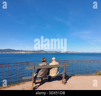 Ein älteres Paar sitzt auf einer Bank und sieht sich Berge an Stockfoto