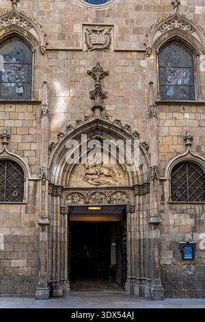 Reich verzierte gotische Steinkirche mit geschnitztem Tympanon, das einen berittenen heiligen darstellt, flankiert von Bogenfenstern und Buntglasfassade, warm verwitterte Fassade Stockfoto