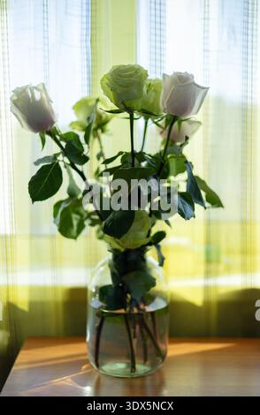 Rosen in einer Vase an einem sonnigen Tag. Ein gemütliches Zuhause. Stockfoto