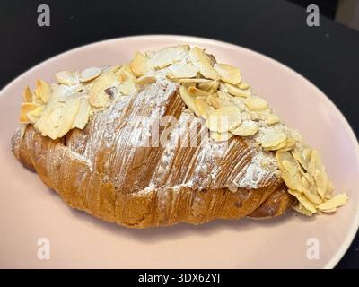 Goldene Croissants mit Mandelscheiben und Puderzucker auf Teller Nahaufnahme. Klassisches Gebäck mit Backtradition, Süße und Blätterteig Stockfoto
