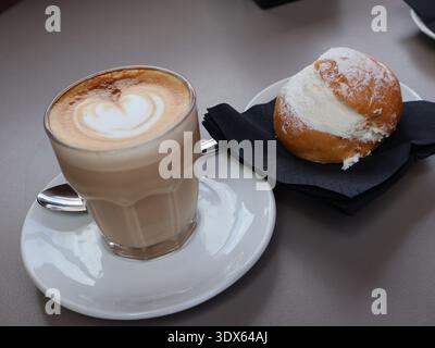 Italienisches Maritozzo-Creme-Brötchen mit Latte und herzförmiger Schaumkunst. Gemütliche Café-Frühstücksszene, romantisches Kaffeepausen-Konzept in Rom, Italien Stockfoto