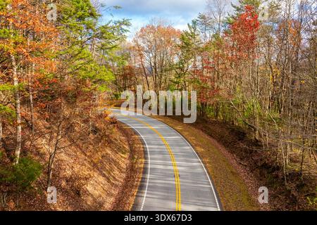 Blue Ridge Parkway bei Sonnenuntergang im Herbst. Malerische Route zwischen majestätischen Berghügeln, die mit goldenen und scharlachroten Blättern bedeckt sind Stockfoto