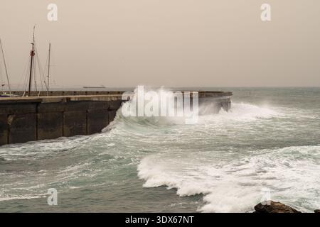 Stürmische Wellen krachen gegen einen Steinpier Stockfoto
