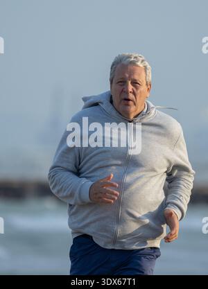 Senior-Mann joggt an der Küste entlang Stockfoto
