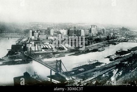 Die Bildunterschrift von 1922 lautet: „The Point – Pittsburgh – malerische Aussicht auf die großartige Stadt am Allegheny River und am Monongahela River, die von der Handelskammer als „Werkstatt der Welt“ bezeichnet wird.“ „The Point“ in Pittsburgh bezieht sich auf den Point State Park (offiziell eröffnet 1974), ein historisches Wahrzeichen, an dem die Flüsse Allegheny und Monongahela den Ohio River bilden und das berühmte „Golden Triangle“ der Stadt mit einem großen Brunnen, Fort Pitt Block House und einem großartigen Blick auf die Stadt bilden. Stockfoto