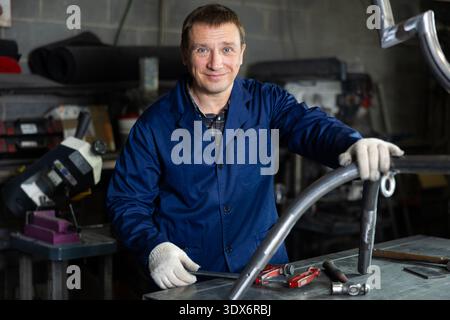 Erfahrener Arbeiter mittleren Alters posiert in einer professionellen Metallwerkstatt Stockfoto