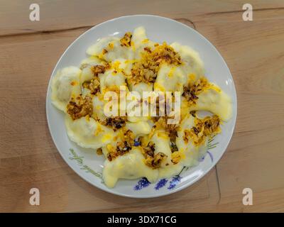 Traditionelle polnische Pierogi-Knödel serviert mit gebratener Zwiebelplatte, hausgemachte osteuropäische Gerichte, die in einer Hausküche zubereitet werden. Stockfoto