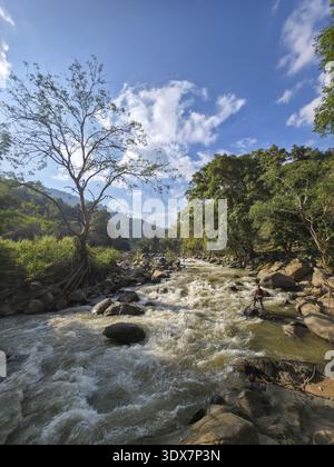 Friedlicher Fluss und Fluss fließen durch die atemberaubende Naturlandschaft. Wunderschöne Wälder, Berge und blauer Himmel schaffen eine ruhige Szene mit klarem Wasser Stockfoto