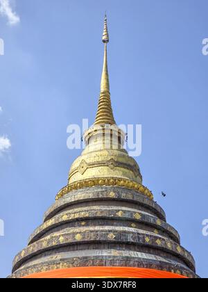 Ruhige goldene Stupa in einem alten Tempel in Thailand. Majestätische buddhistische Architektur steht vor klarem Himmel, spirituellem und friedlichem Denkmal der Fait Stockfoto