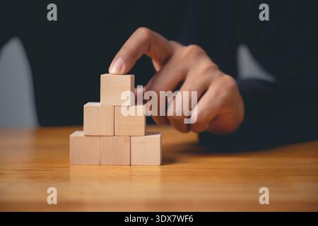 Diese Nahaufnahme zeigt ein starkes Zeichen des Wachstums, dass eine Männerhand mit Geste posiert, um eine Pyramide zu bauen, ein klares Geschäftszeichen für strategische Planung und Zukunft Stockfoto