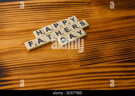 Die Leute versammeln sich um einen Holztisch, um Scrabble am National Scrabble Day zu spielen. Sie platzieren Buchstabensteine, um Nachrichten zu buchstabieren und genießen das Spiel gemeinsam. Stockfoto
