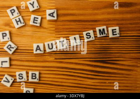 Am National Scrabble Day versammeln sich die Spieler an einem Holztisch, um das Wortspiel zu genießen. Die Buchstaben schreiben einzigartige Wörter aus, was Spaß und Lernspaß fördert Stockfoto