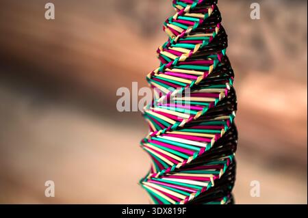 Kunsthandwerk mit natürlichem Stroh .Strohspirale Hintergrund. Draufsicht. Goldene Spirale. Eine Spirale, ein Drehteller, gewebt aus buntem Stroh. Stockfoto