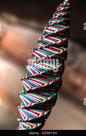 Kunsthandwerk mit natürlichem Stroh .Strohspirale Hintergrund. Draufsicht. Goldene Spirale. Eine Spirale, ein Drehteller, gewebt aus buntem Stroh. Stockfoto