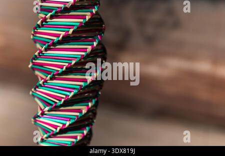 Kunsthandwerk mit natürlichem Stroh .Strohspirale Hintergrund. Draufsicht. Goldene Spirale. Eine Spirale, ein Drehteller, gewebt aus buntem Stroh. Stockfoto