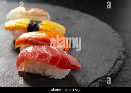 Nahaufnahme von erstklassigem japanischem Nigiri-Sushi auf einer dunklen Schiefersteinplatte Stockfoto