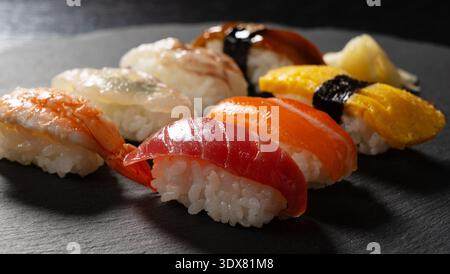 Verschiedene traditionelle japanische Nigiri-Sushi auf einem dunklen Schieferteller Stockfoto