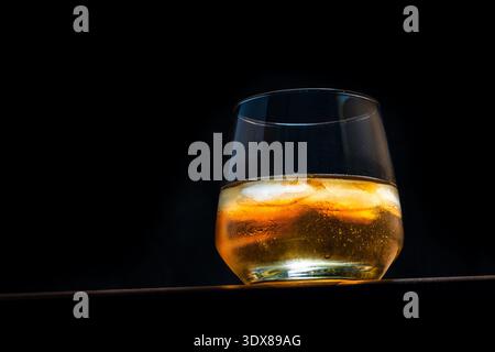 Glas Whiskey mit Eis auf dunklem Hintergrund Stockfoto